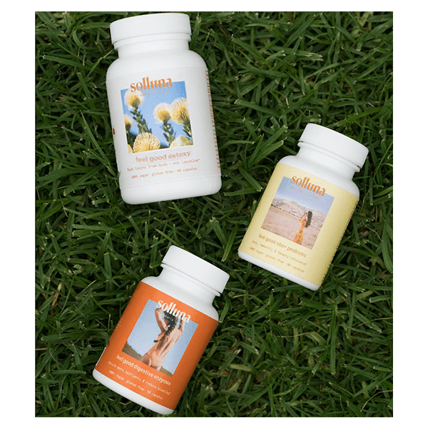 Feel Good Starter Kit bottles include Detoxy 2.0, Digestive Enzymes and SBO Probiotics laying in the grass